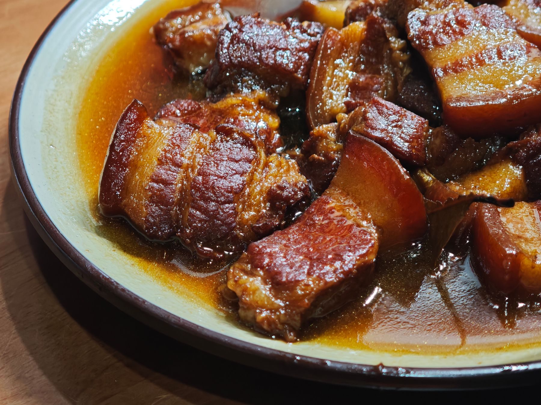 Pork belly braised to a dark lacquer in caramel and fish sauce, in a shallow clay dish